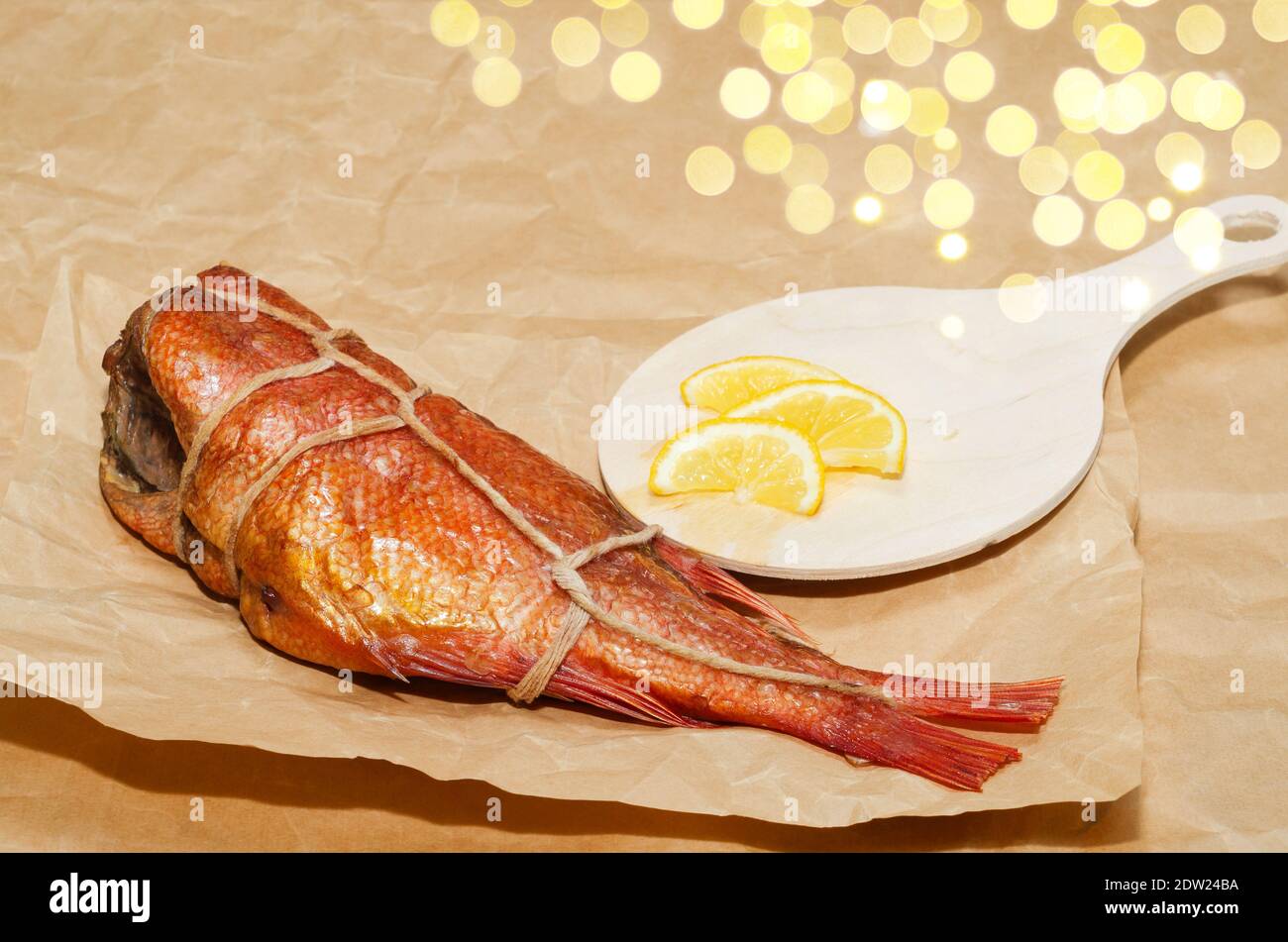 Hot smoked sea bass with lemon, closeup on the background of crumpled