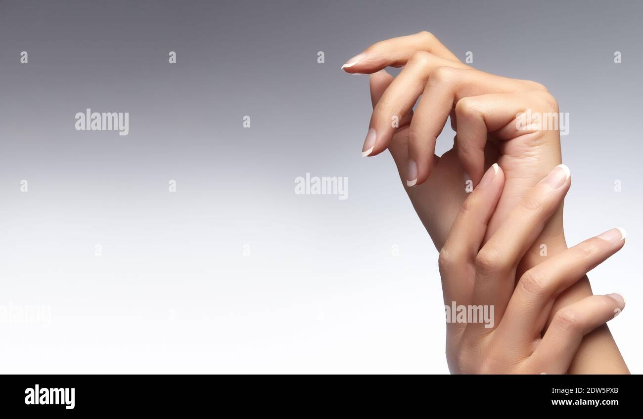 Beautiful woman's hands on light background. Care about hand. Tender palm with natural manicure, clean skin. French nails. Horizontal shot with copy s Stock Photo