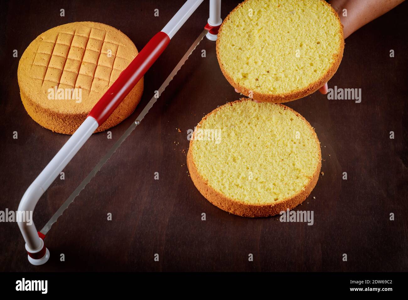 Baker cutting the top of cake with a serrated leveler cake. Making a