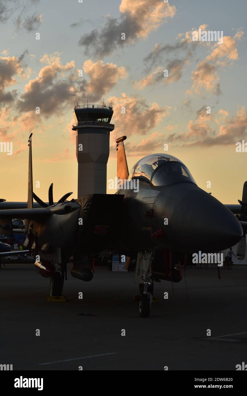 F-15 fighter jet on tarmac in Boeing Plaza at sunset, radio control tower in distance, at EAA AirVenture, Oshkosh, Wisconsin, USA Stock Photo