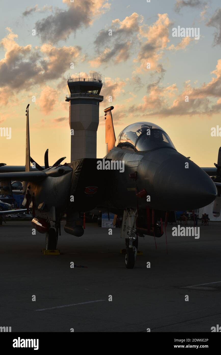 F-15 fighter jet on tarmac in Boeing Plaza at sunset, radio control tower in distance, at EAA AirVenture, Oshkosh, Wisconsin, USA Stock Photo