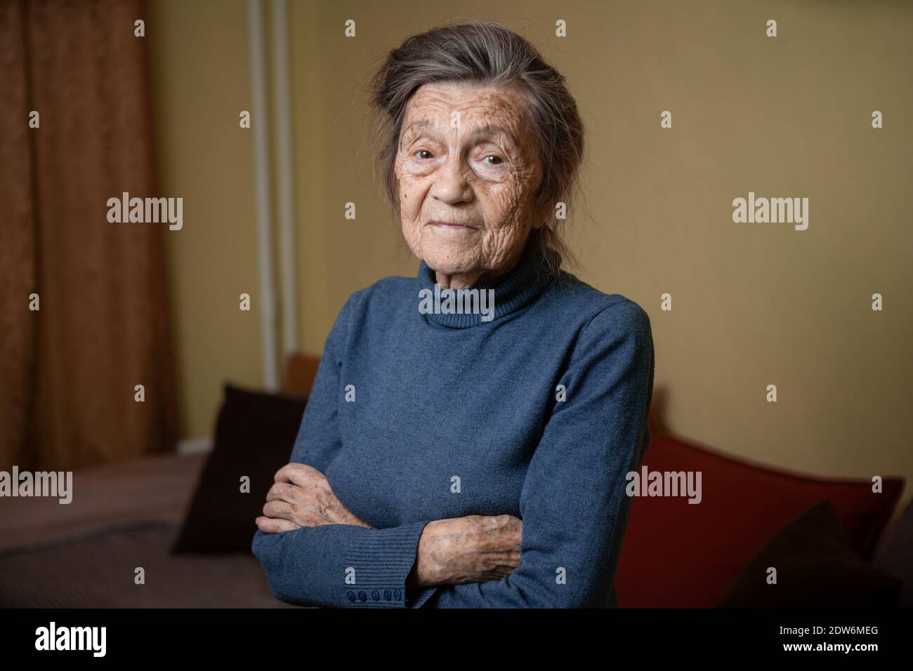 Elderly Caucasian senior grandmother ninety years old looks attentively and smiles, feels happy, large portrait, face with deep wrinkles, gray hair. T Stock Photo