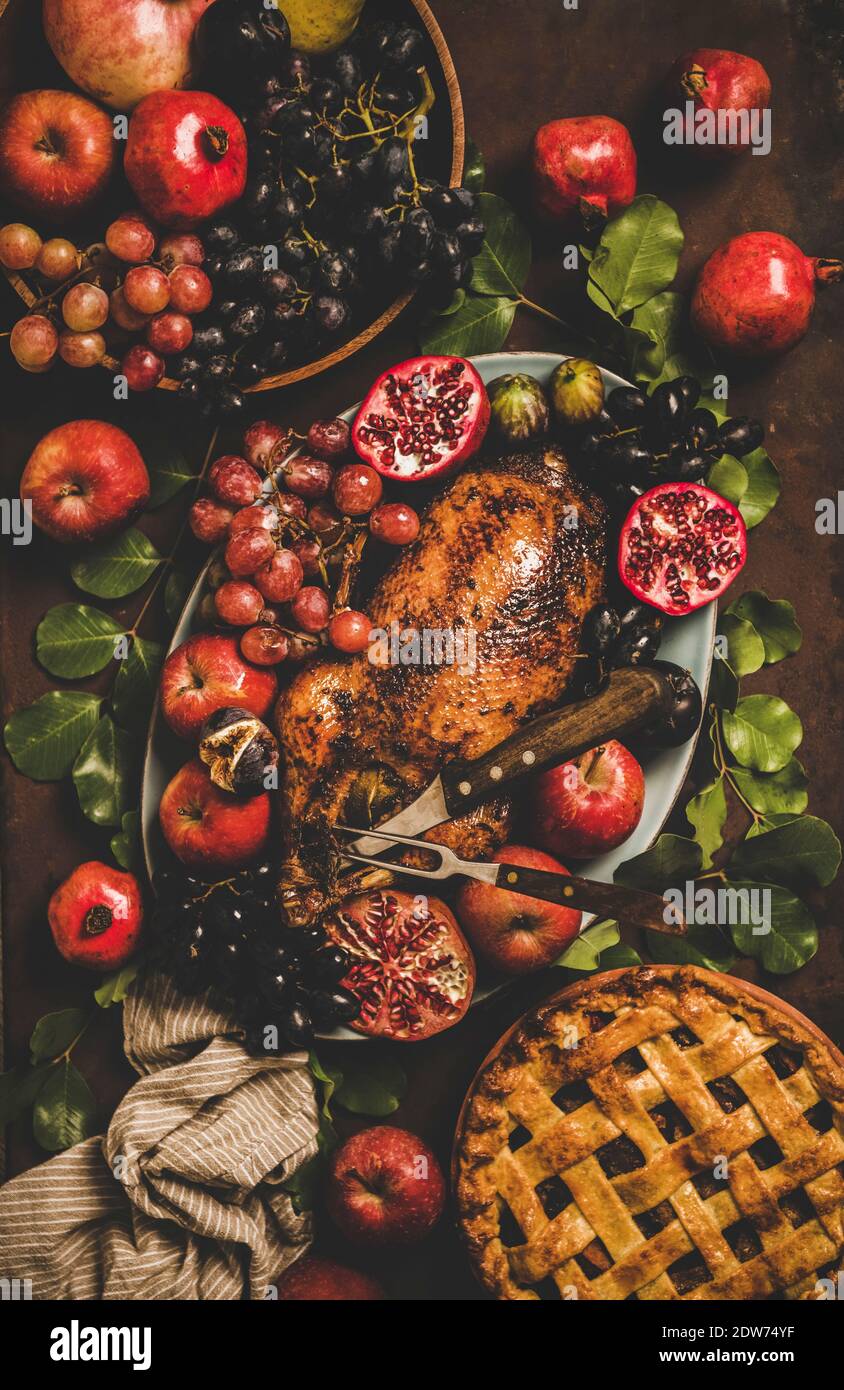 Autumn Thanksgiving, Friendsgiving, family gathering dinner. Flat-lay of Fall table with roasted duck in seasonal fruits and apple pie decorated with Stock Photo