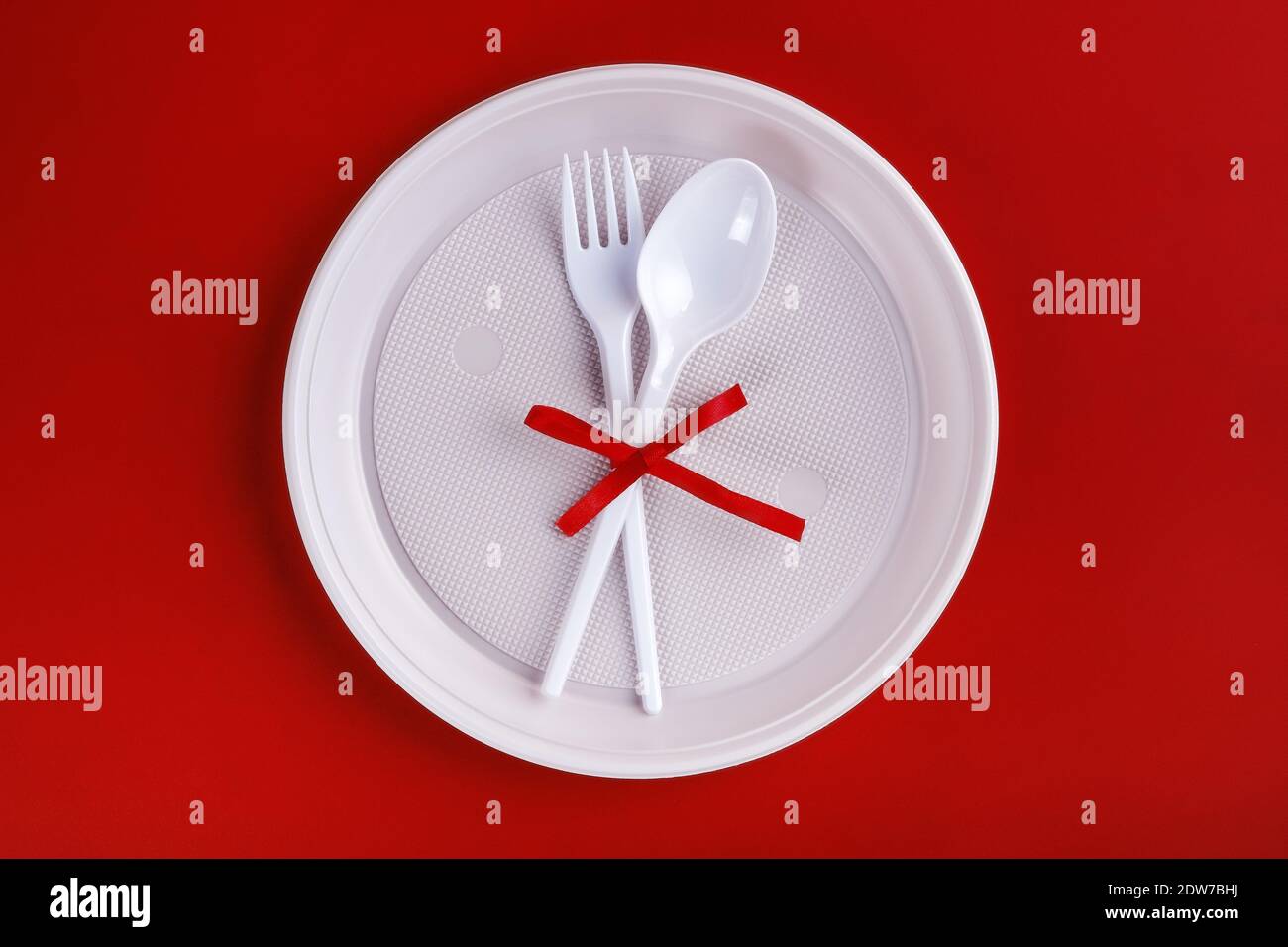 Top view of plastic white disposable fork and spoon tied with red ribbon Stock Photo