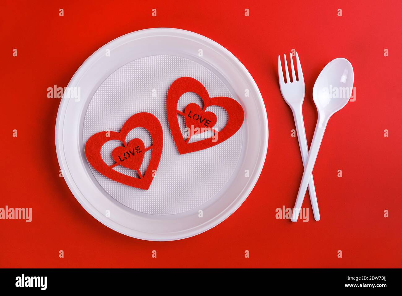 Top view of plastic white disposable fork, spoon, plate and red hearts isolated  Stock Photo