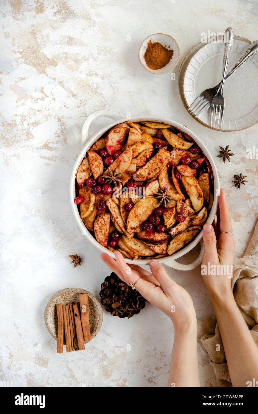 Baked apple and cranberry dessert with hands holding the dish. Stock Photo