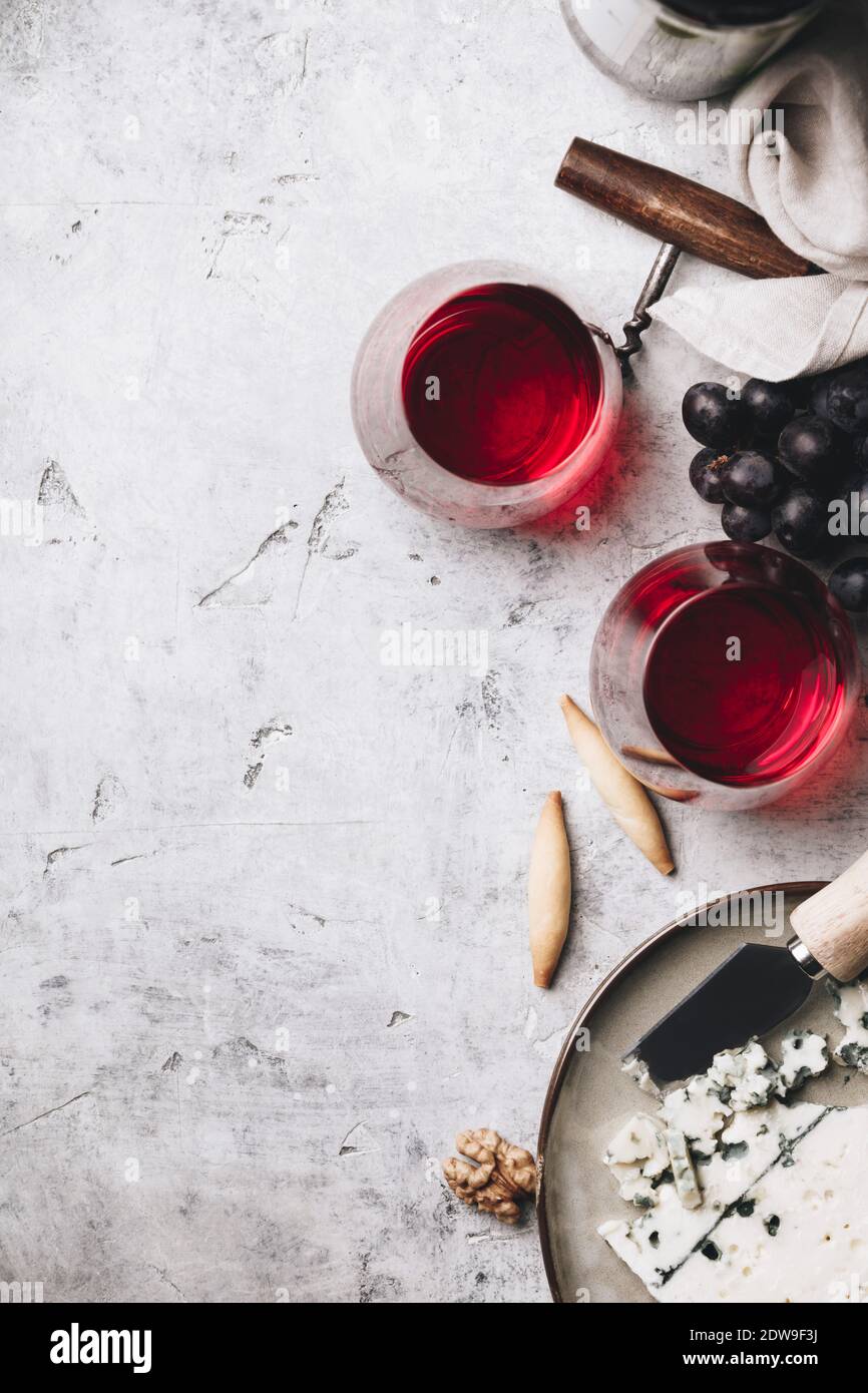 Glasses of red wine, cheese and grapes on rustic concrete background, copyspace, flat lay Stock Photo