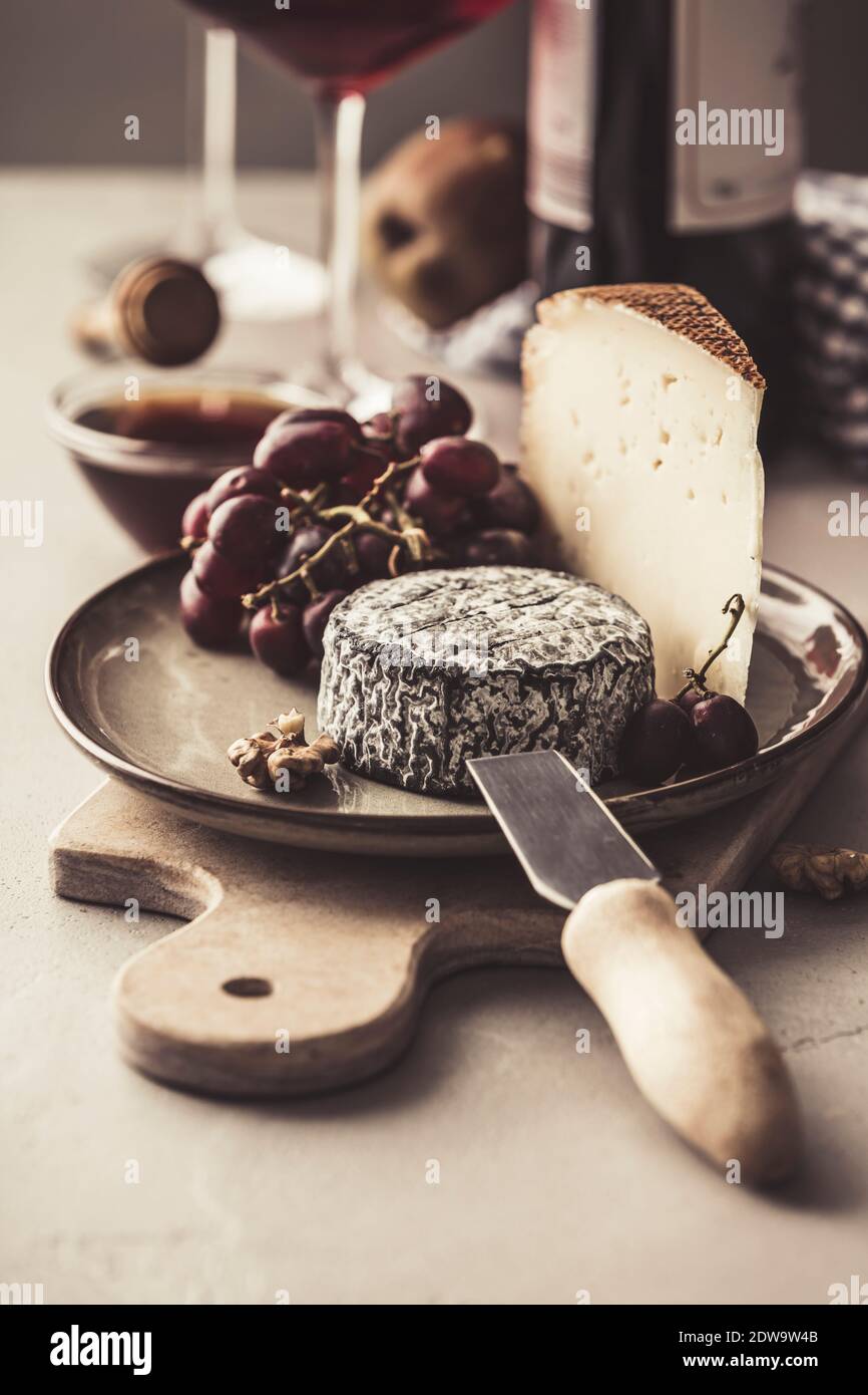 Red wine and cheese plate with fruits and nuts on concrete background Stock Photo