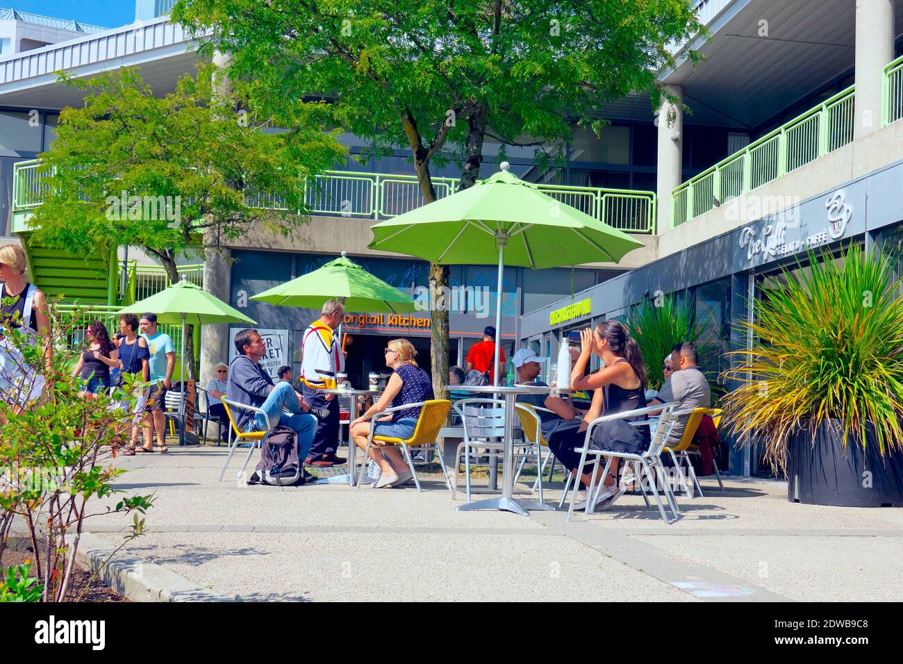 People sitting at an outdoor cafe under green umbrellas during the summer.  Stock photo. Stock Photo