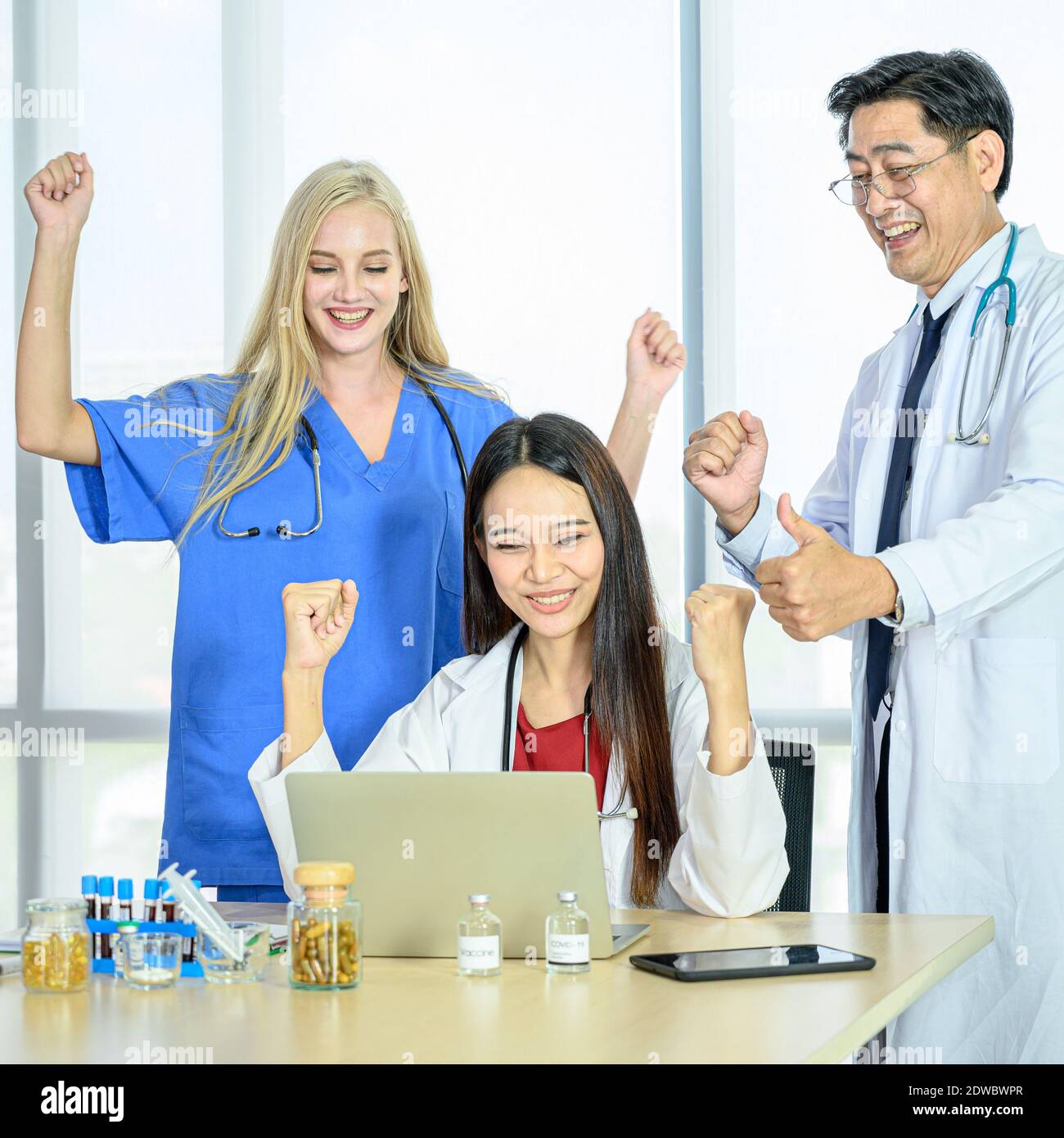 Group of doctors wearing formal white coat and blue scrubs suit, Thumbs up for success at the hospital. Healthcare specialist people. Stock Photo