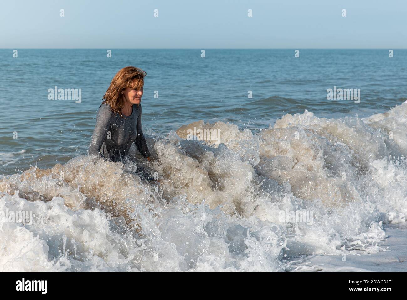 Woman coming out of the sea in a wet dress after a swim at the beach ...