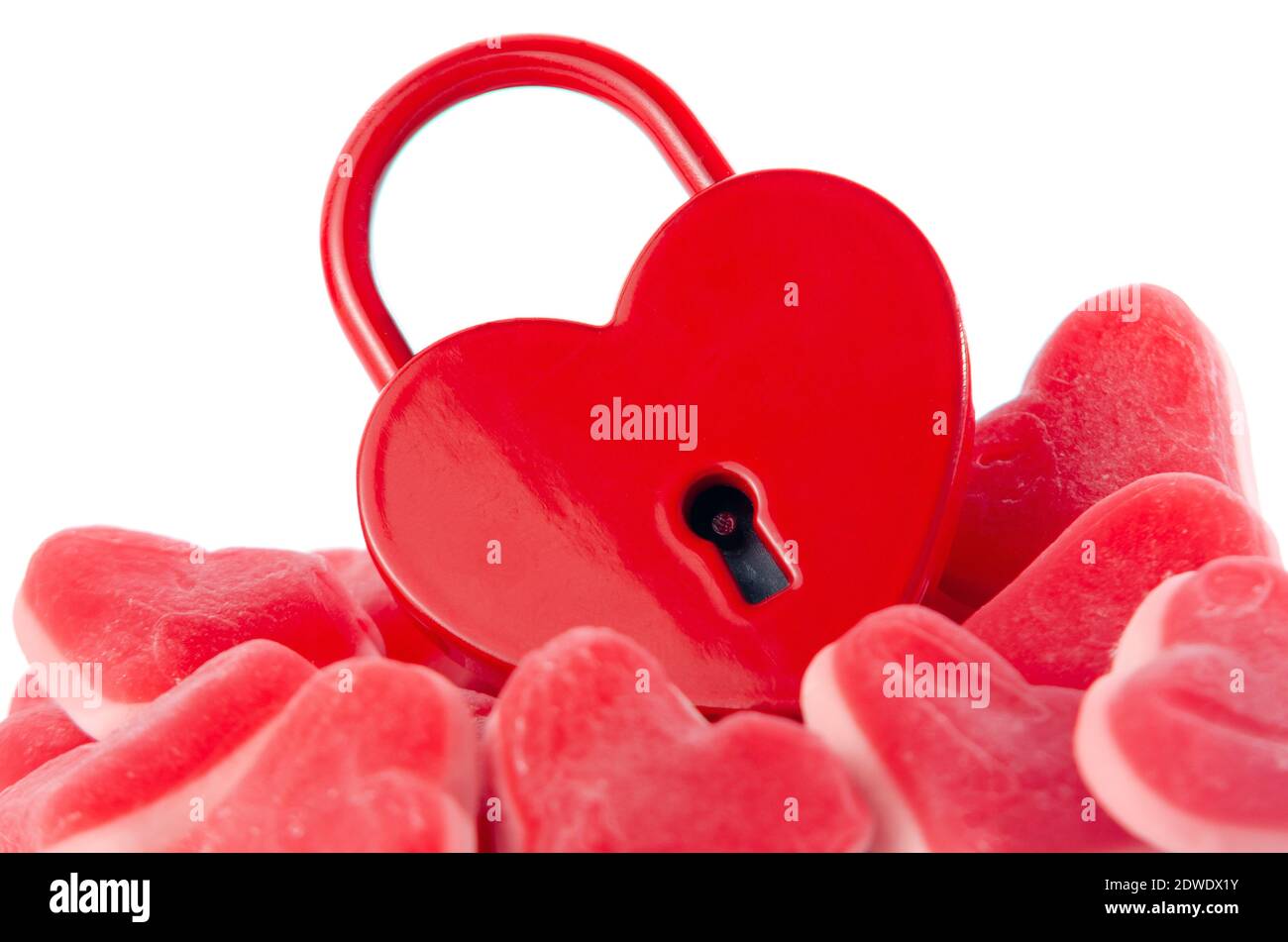 Close-up Of Heart Shape Lock With Candies Over White Background Stock Photo