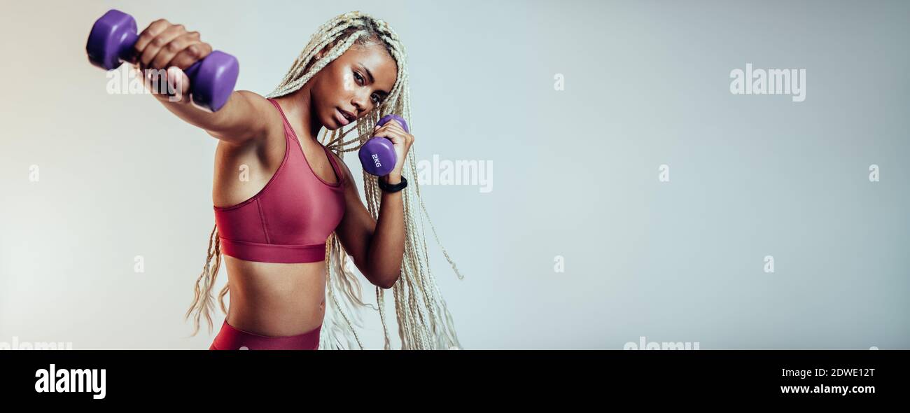 Close up of fitness woman doing fitness training using dumbbells. African american woman working on muscle training using dumbbells. Stock Photo