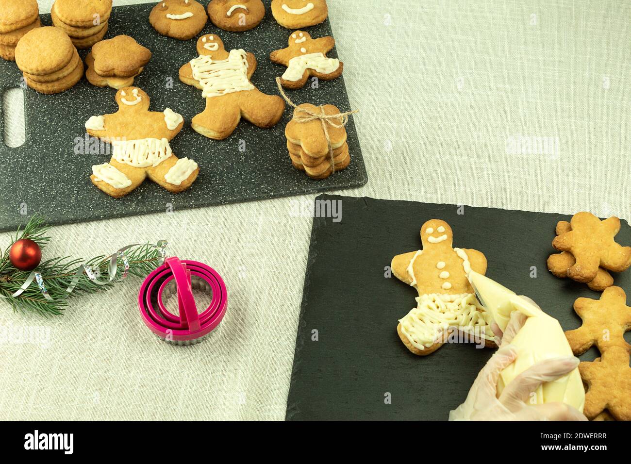 The girl applies cream to Christmas cookies. Decorating Christmas cookies with a pastry bag. Girl decorates cookies with interest Stock Photo
