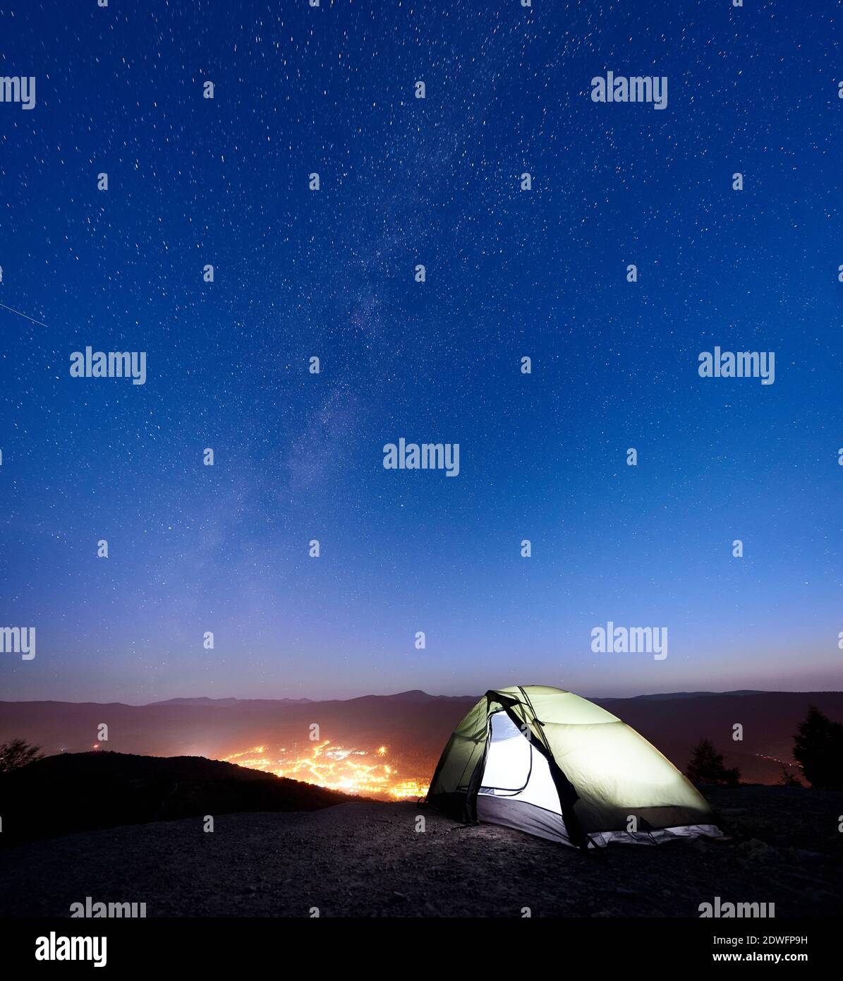 Tourist camping on the top of mountain in the morning. Illuminated tent ...