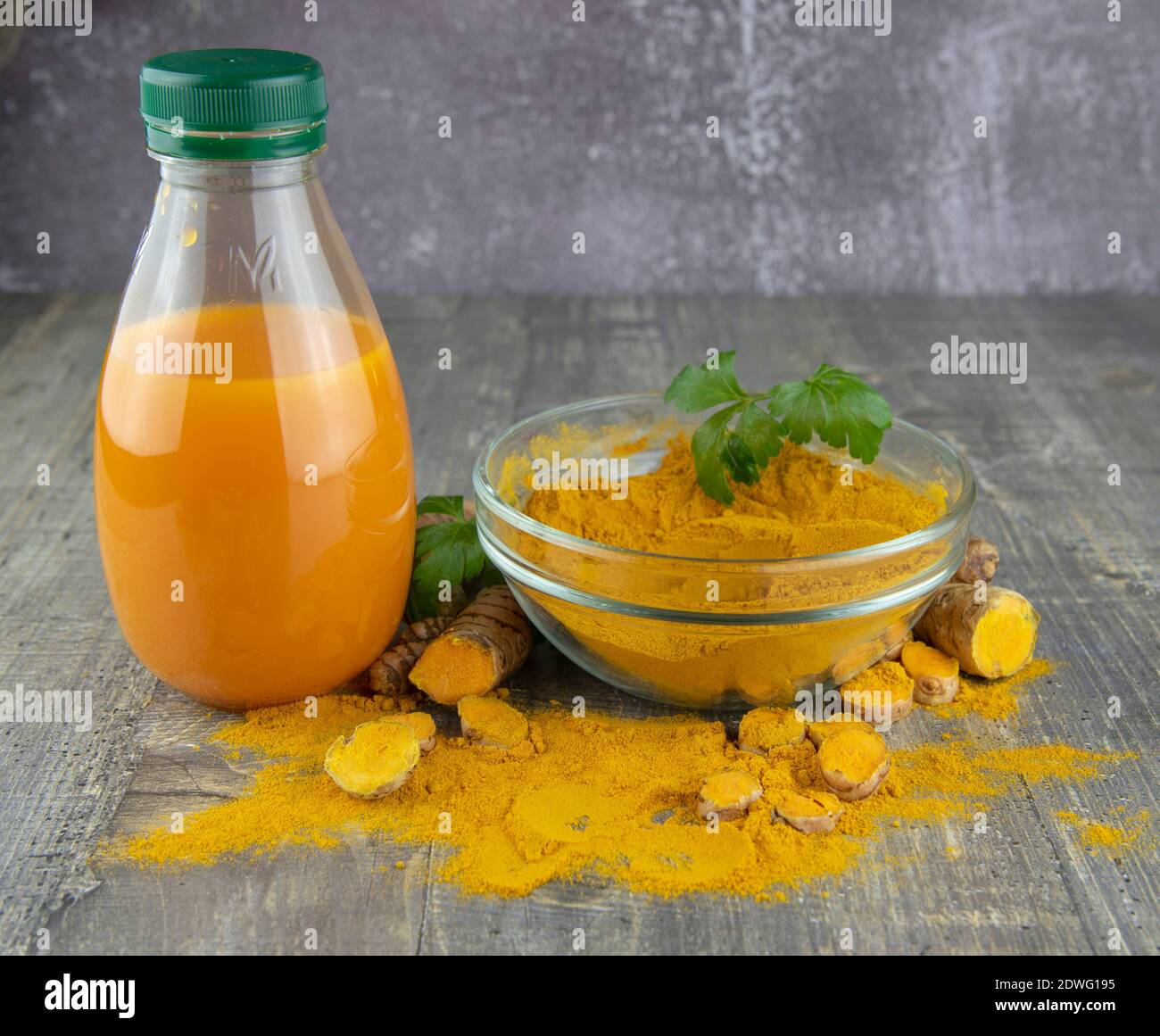 Turmeric juice in a bottle and turmeric powder on a wooden background