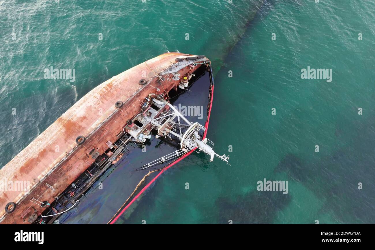 A sunken tanker that hit the shore with a storm. Coastal pollution by oil. Ecological catastrophe. Stock Photo