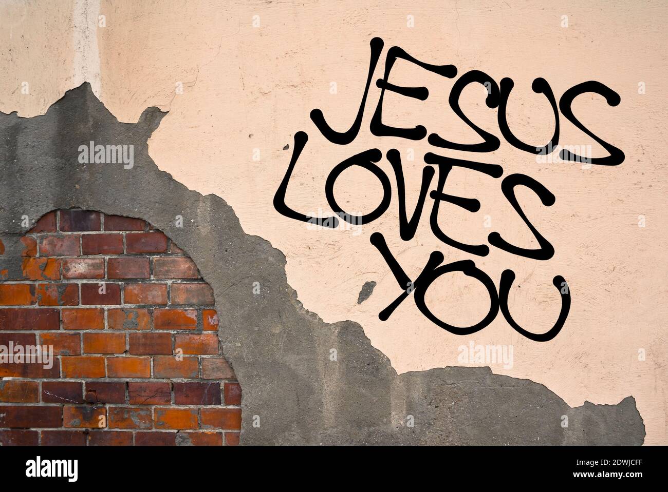 Jesus Loves You - handwritten graffiti sprayed on the wall, anarchist aesthetics - Christianity and Chist's unconditional love to everybody, including Stock Photo