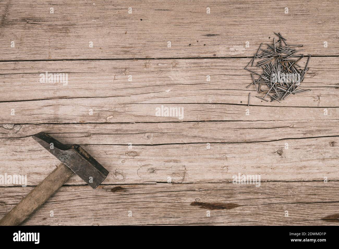 old wooden background with hammer and many stacked small nails Stock Photo