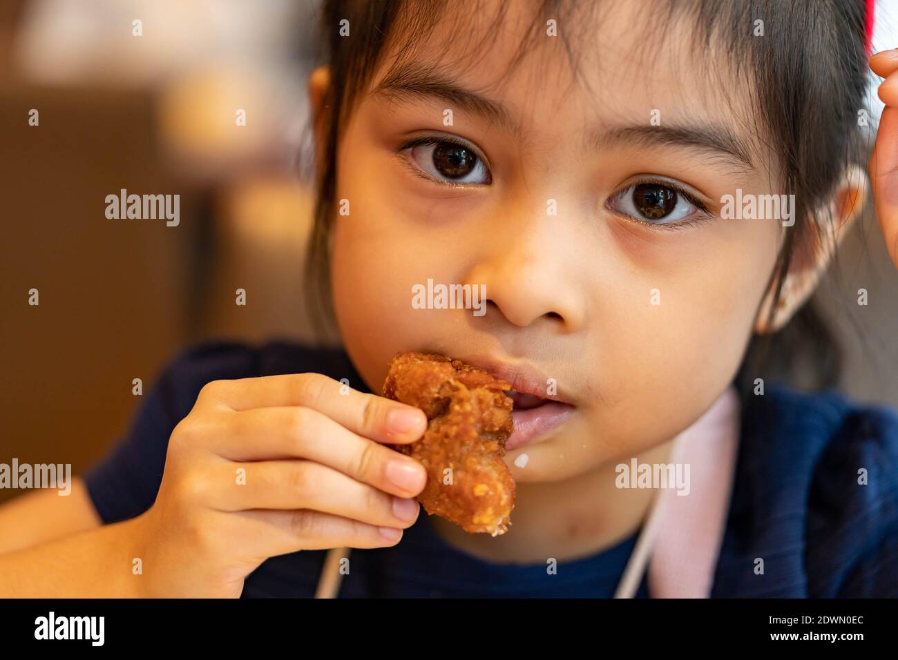 Asian girl Eating Chicken. child eating a chicken nuggets Stock Photo
