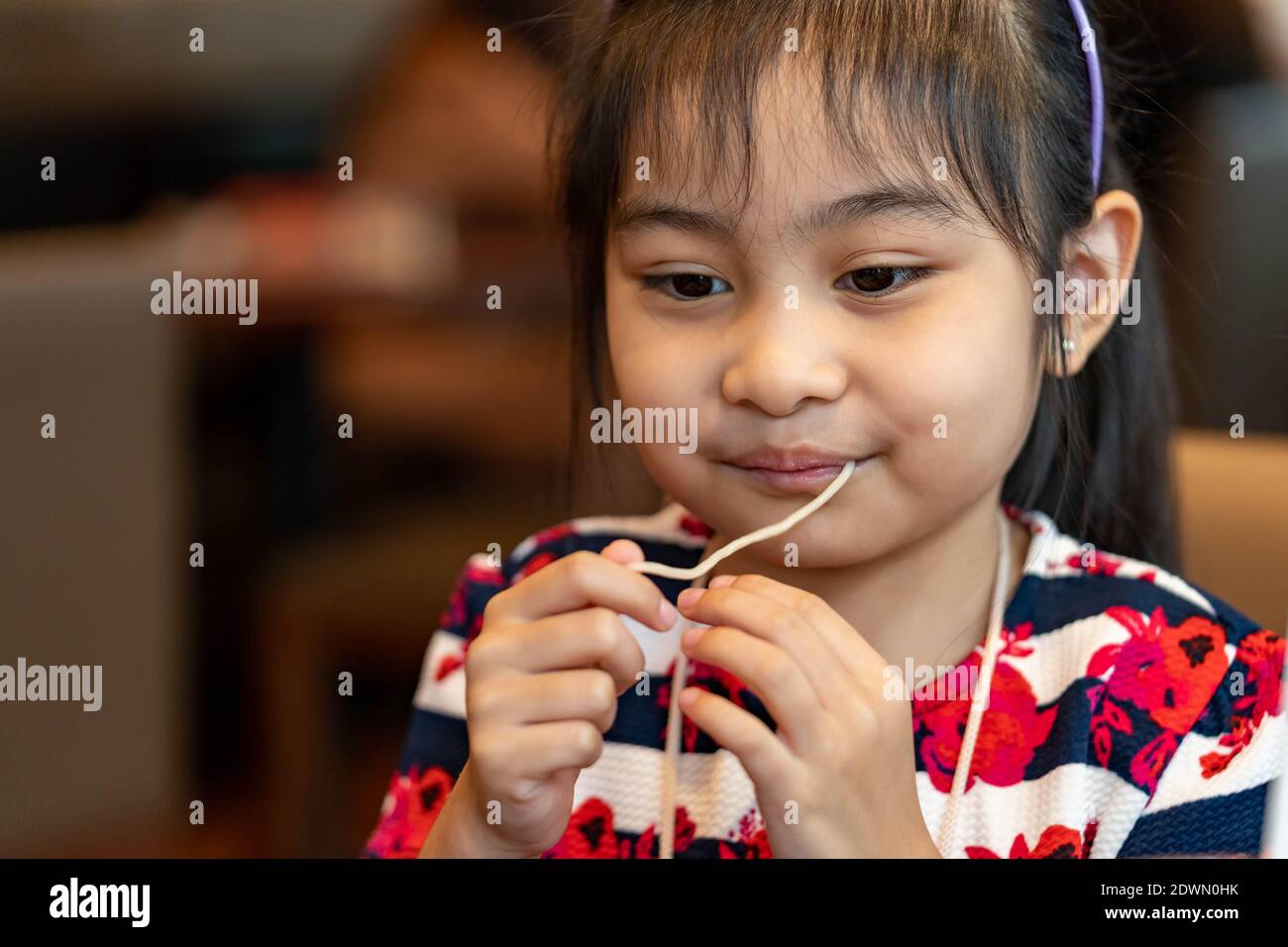 Female asian child while eating noodles. Child eating ramen noodles ...