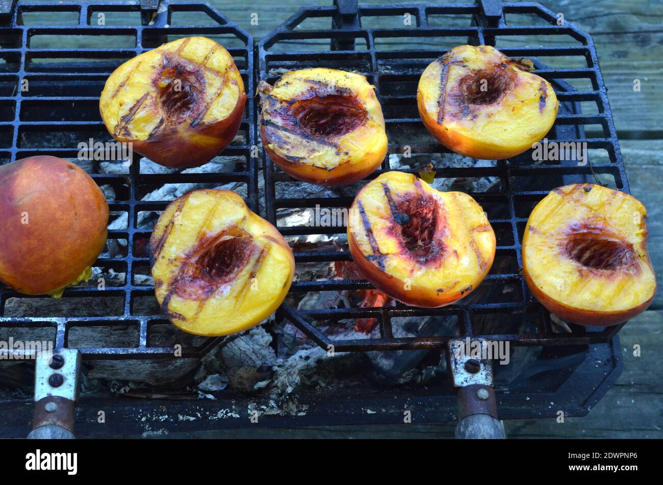 Peach Halves Grilling On Top Of A Small Tabletop Hibachi Grill On