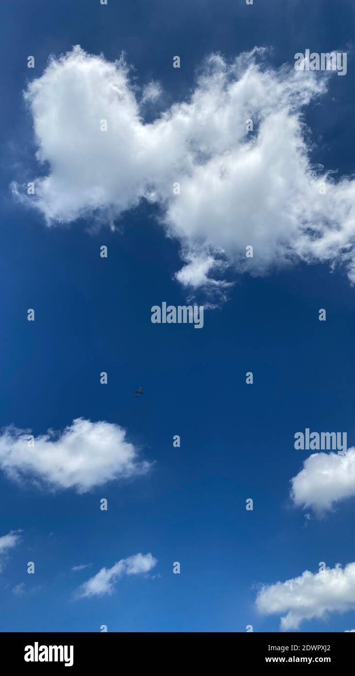 Airplane flying in the blue sky among clouds and sunlight Stock Photo ...