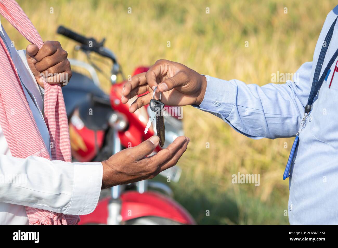 Close up of Farmer hands receiving keys from banker or corporate officer - concept of farmer bike or two wheeler loan Stock Photo