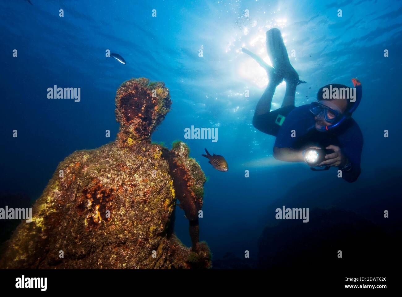 Scuba diver swimming above a submerged ancient roman statue. Underwater