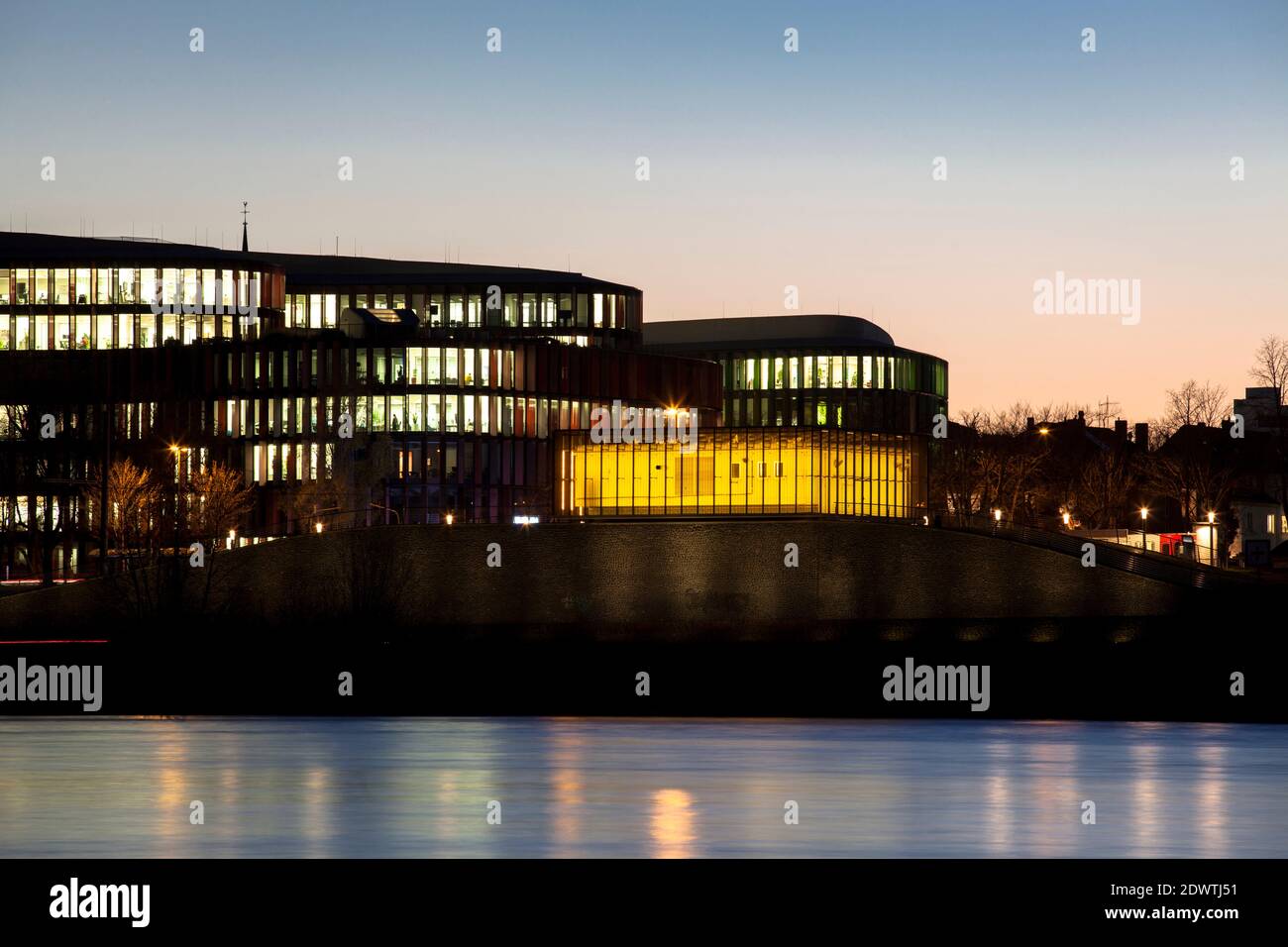 view over the river Rhine to the office building Cologne Oval Offices and the yellow illuminated flood pumping station in the district Bayenthal, Colo Stock Photo