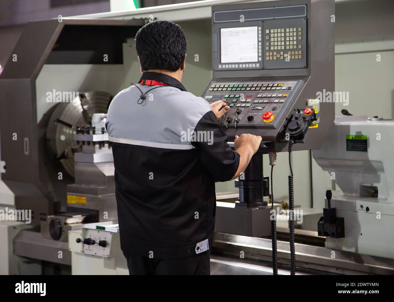 Industrial technician operating CNC lathing machine. Metalworking