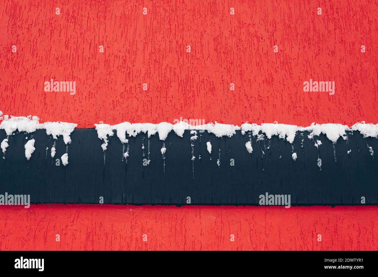 The wall texture is red with a black band covered in snow. Stock Photo
