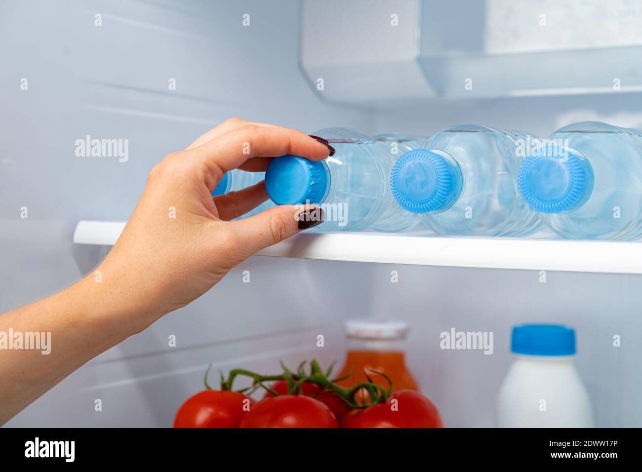 Female hand taking bottle of water from a fridge Stock Photo Alamy