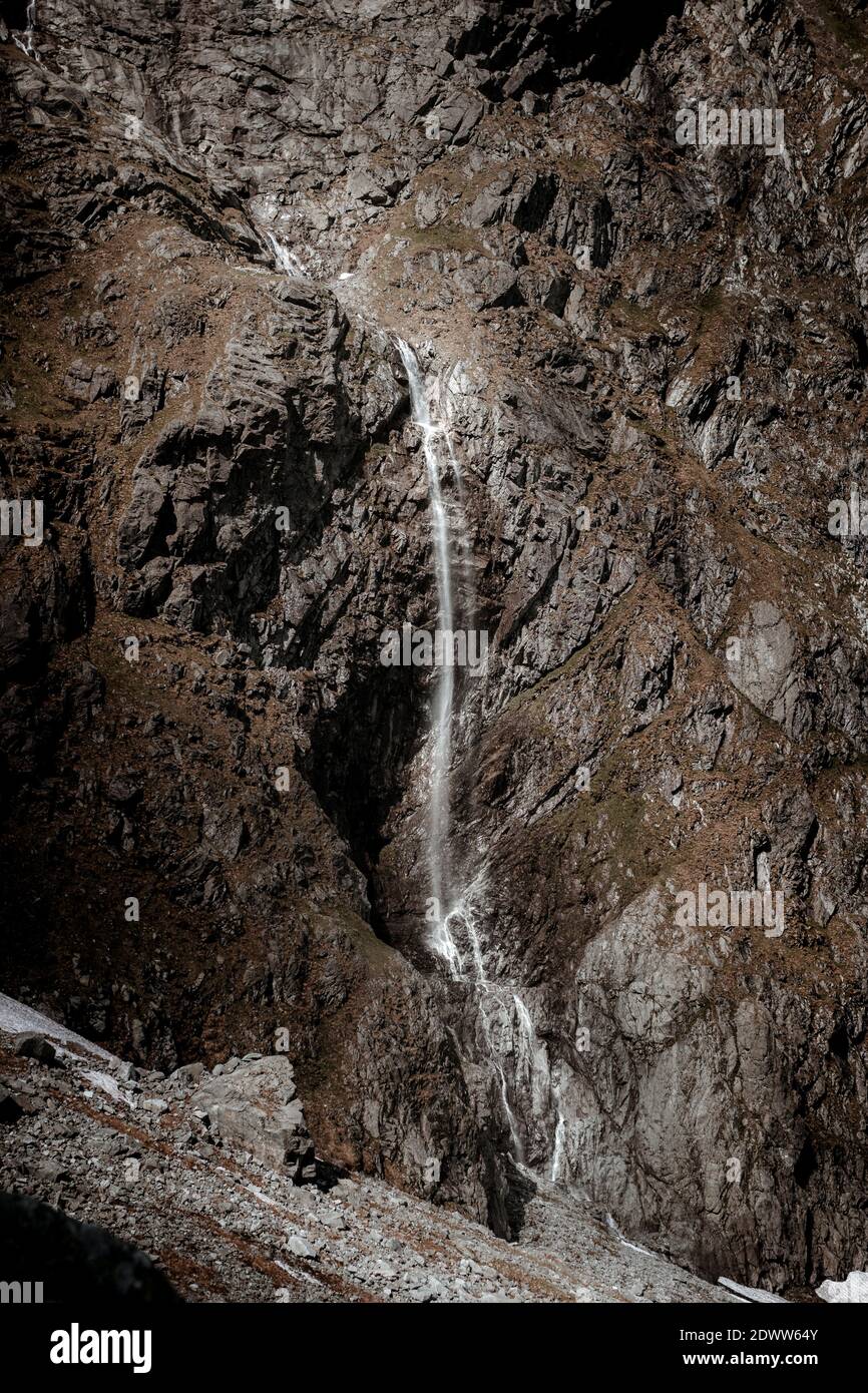 A vertical shot of a waterfall flowing through rocky cliffs Stock Photo ...