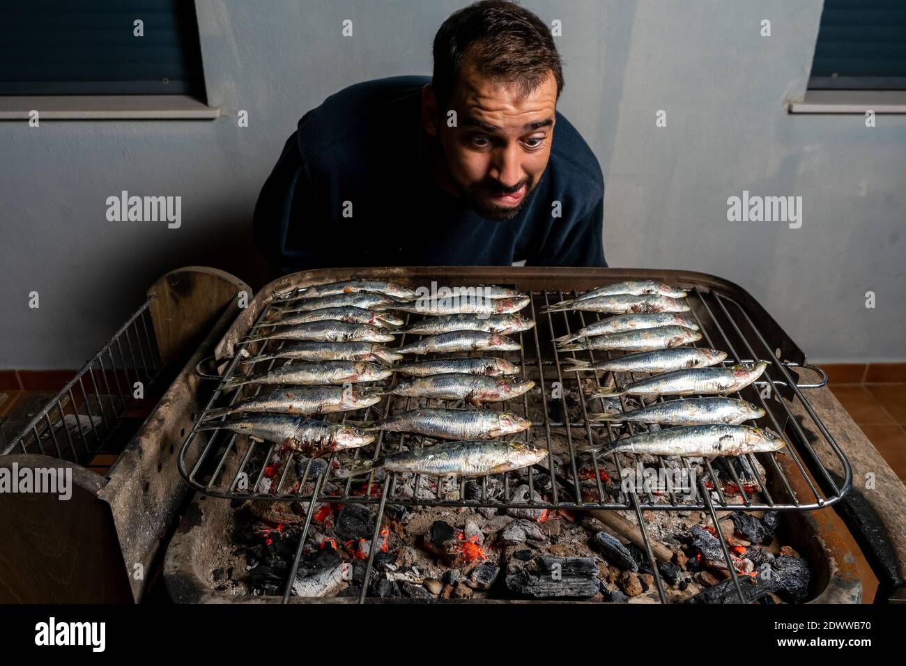 Man cooking a barbecue of fresh sardines on a charcoal barbecue