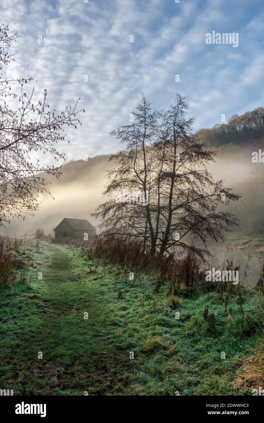 Boat house alongside a mist covered river Wye at Brockweir Stock Photo