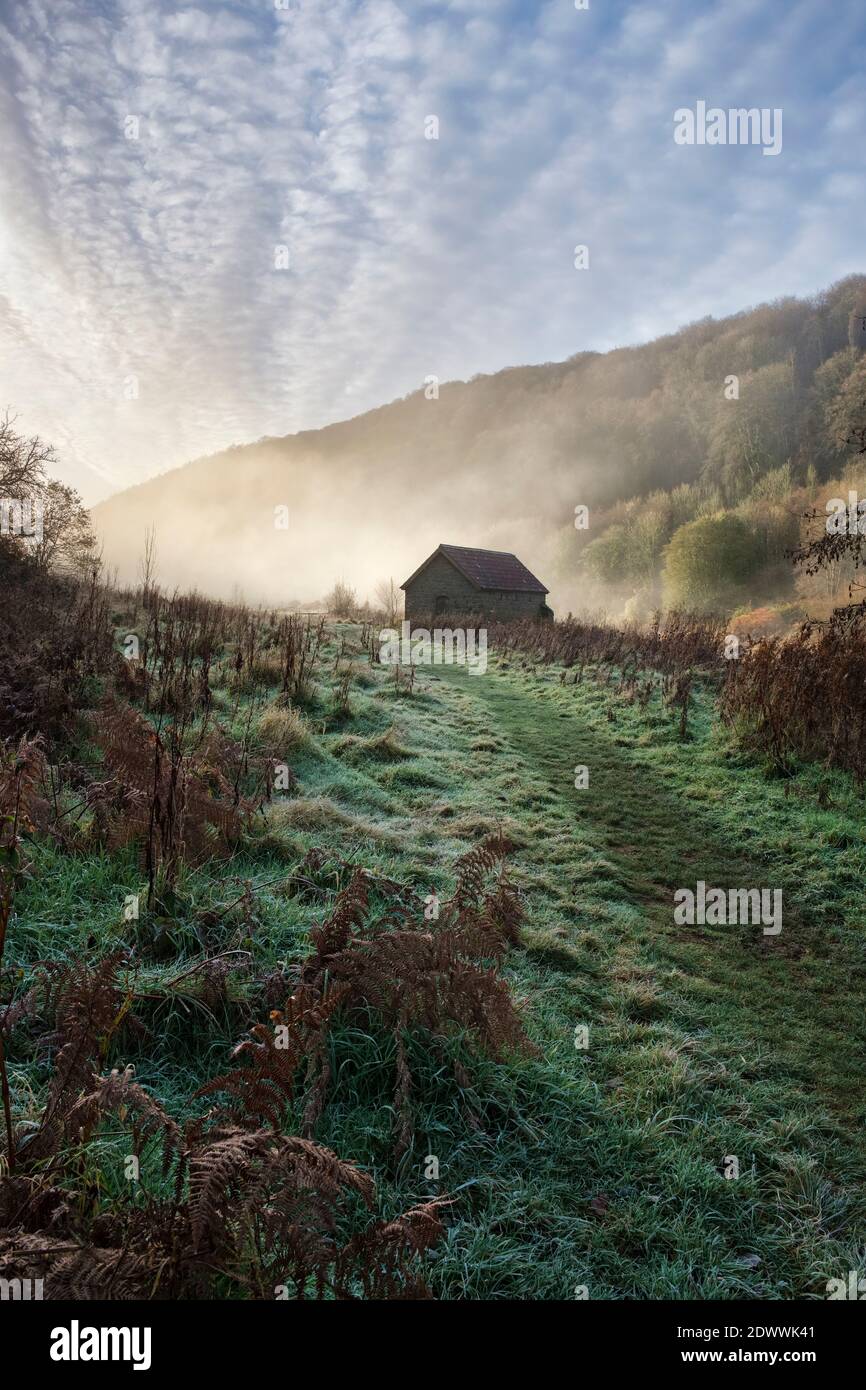 Boat house alongside a mist covered river Wye at Brockweir Stock Photo