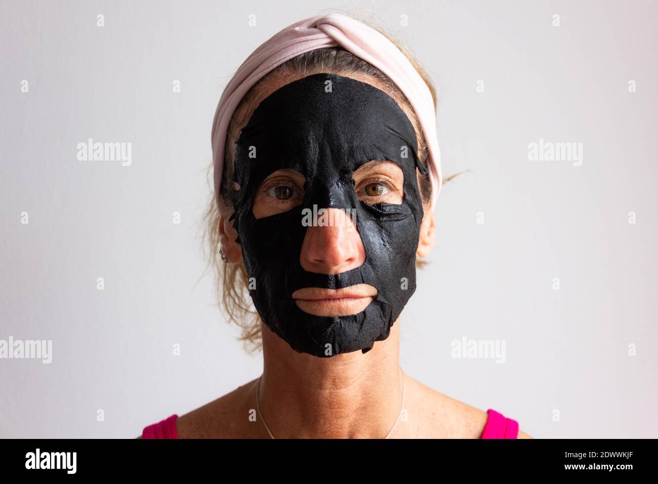 Portrait of middle aged woman applying facial beauty mask. Skinny lady getting skin care self treatment. Anti aging, health care concepts Stock Photo