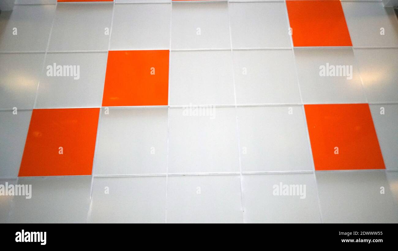 A white wall with an orange tile. Selective focus Stock Photo