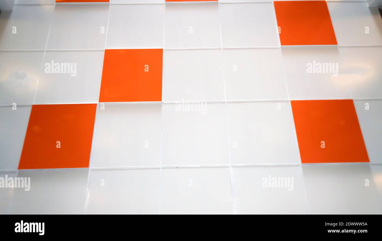A white wall with an orange tile. Selective focus Stock Photo