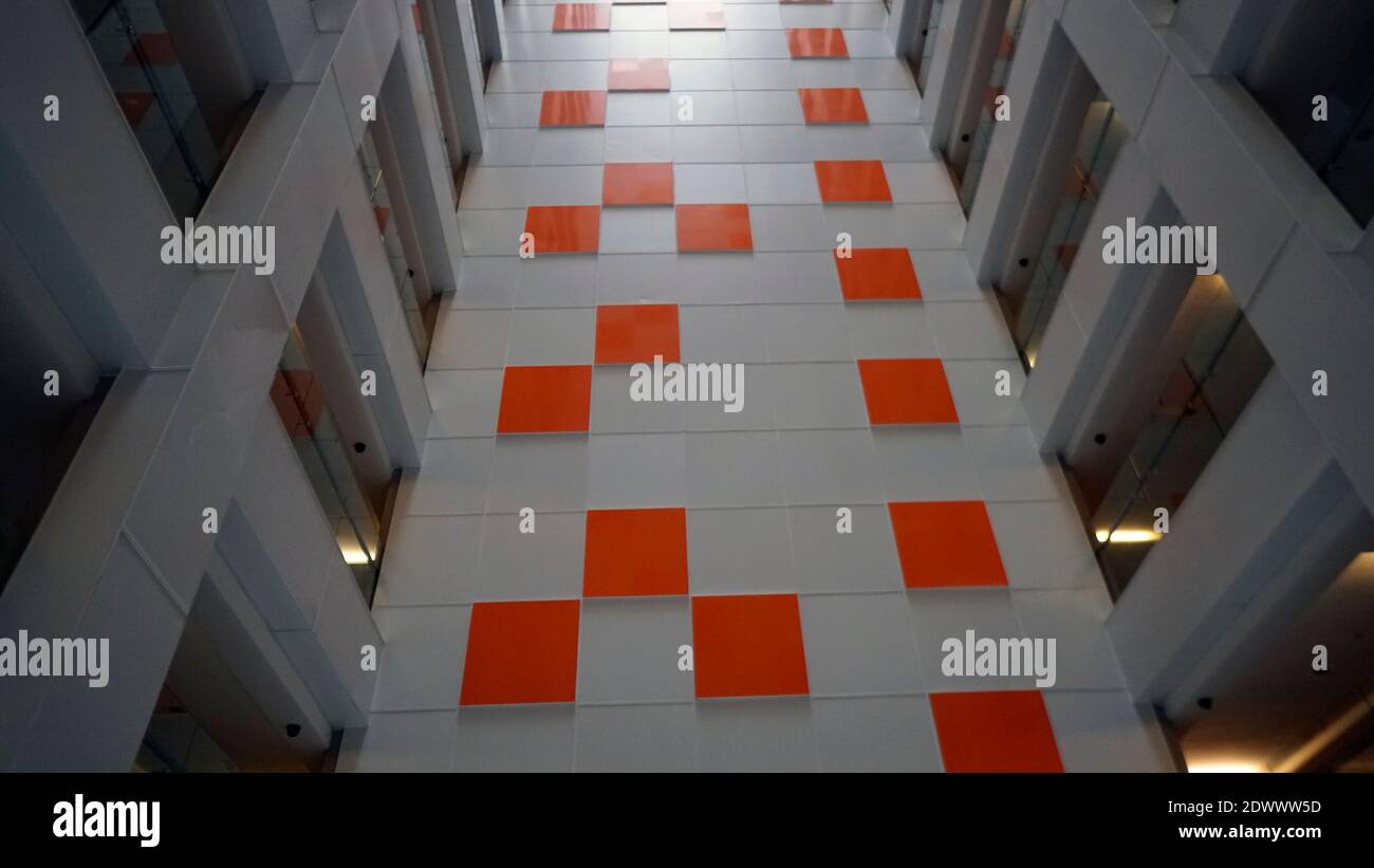 A white wall with an orange tile. Selective focus Stock Photo