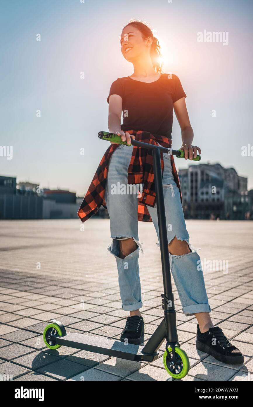 young teenager in sneaker on modern extreme stunt kick scooter in city Stock Photo