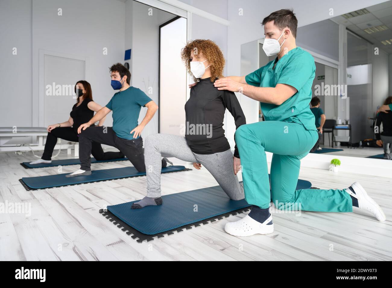 Group of persons on yoga mats assisted by physiotherapist at the rehabilitation clinic. High quality photo Stock Photo
