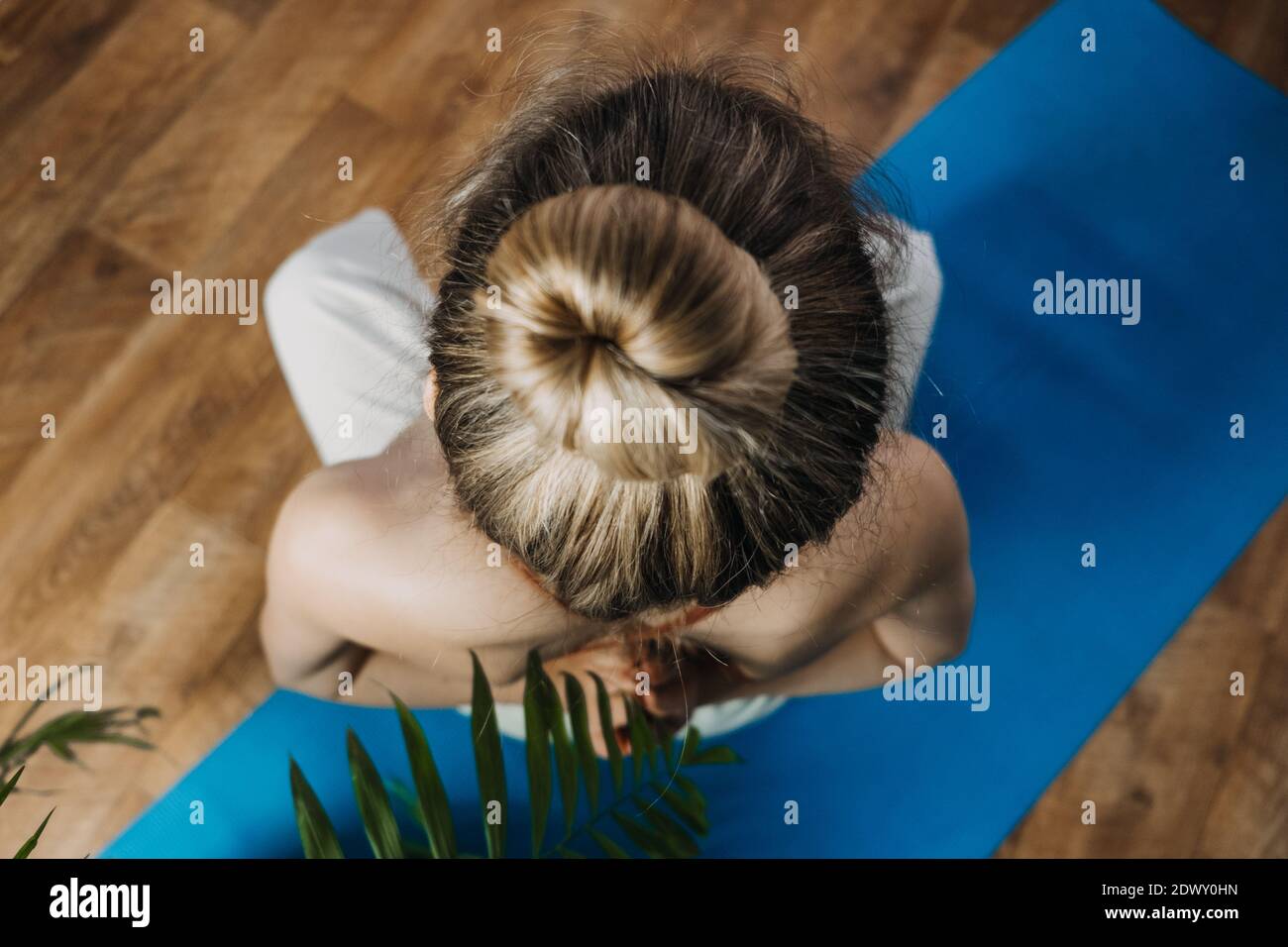 Back view of young woman in sportswear sitting in lotus position while ...