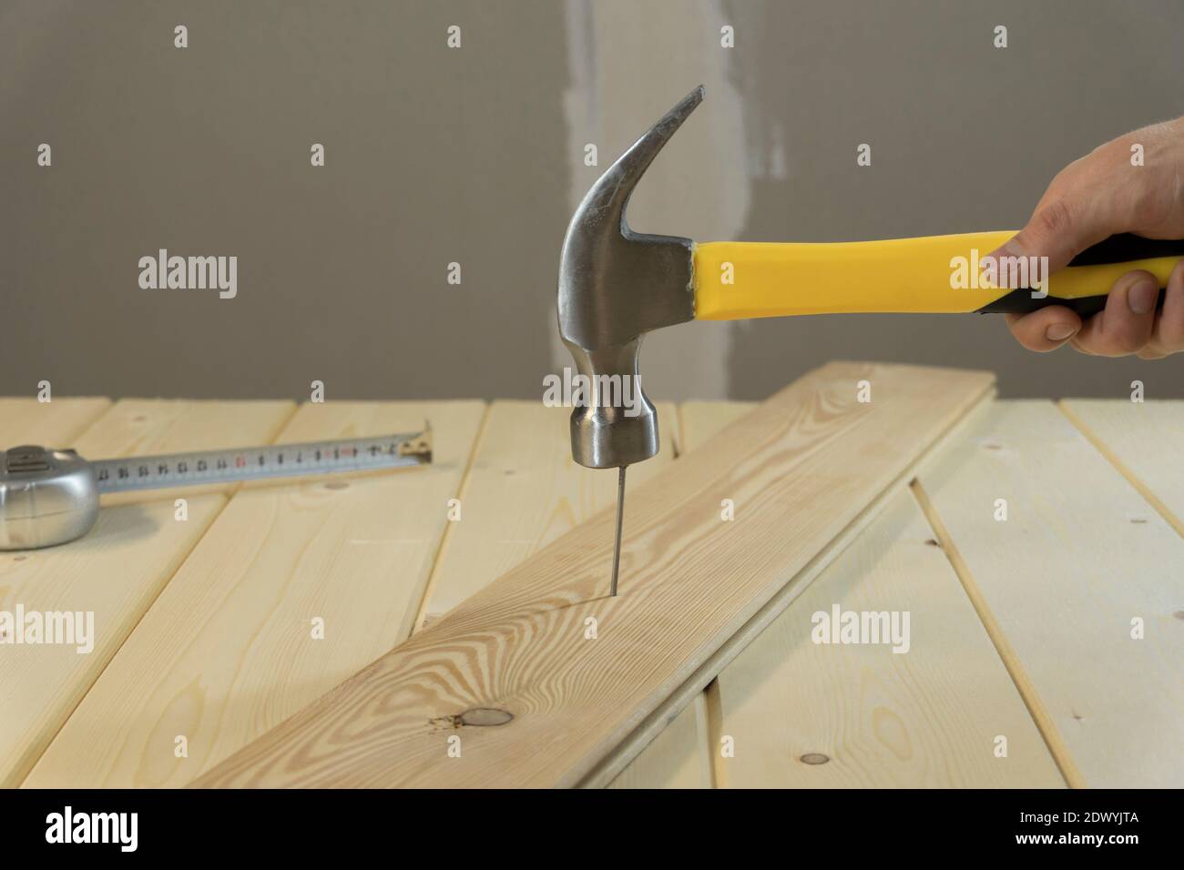 Hammer Hitting Nail On The Head. DIY. Carpenter hands with hammer wood and nail. Using hammer on wood backdrop. Tools for home repair. Fix the house. Stock Photo