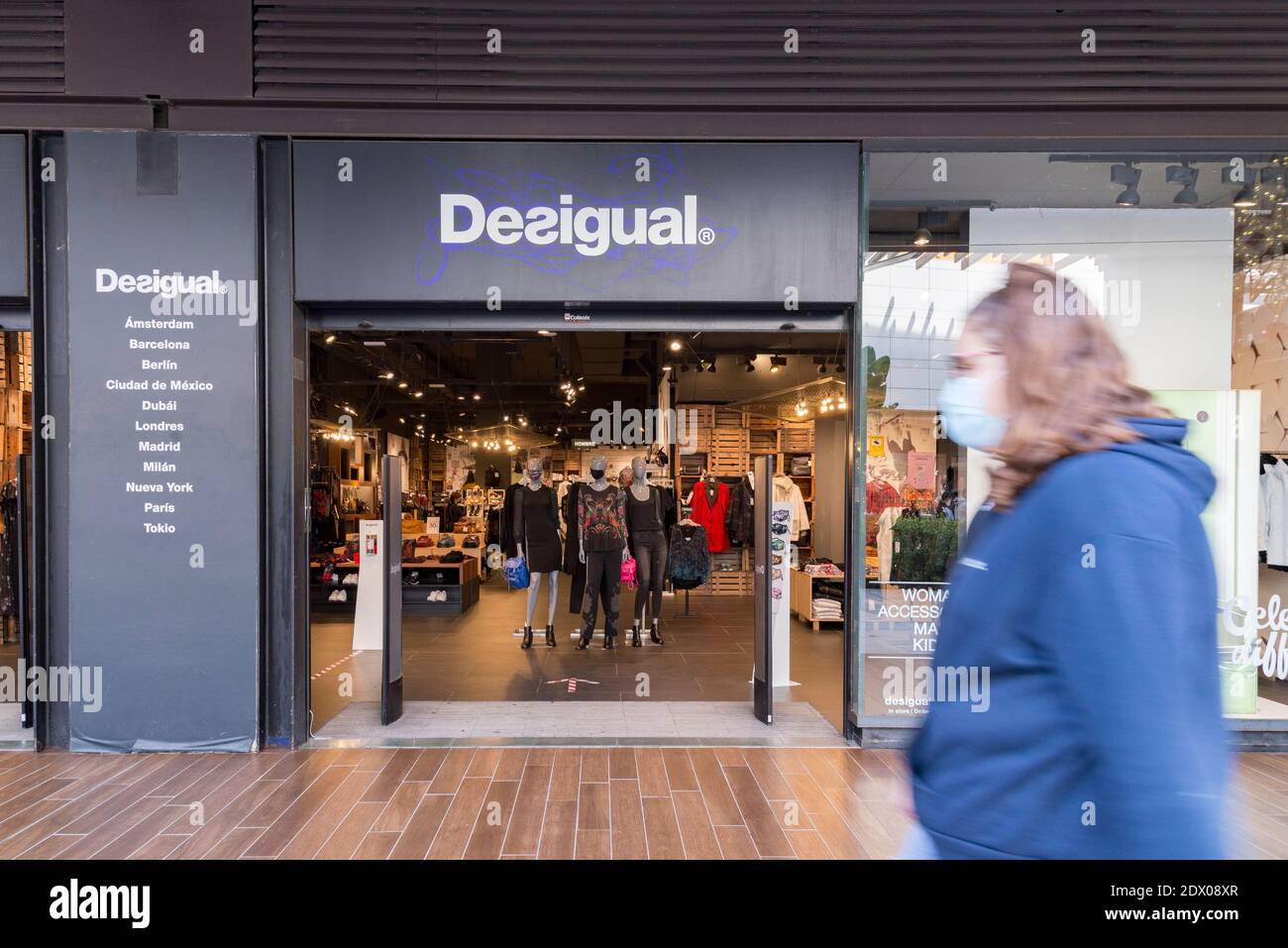 A woman wearing a face mask walks past the Desigual store at the Bonaire  shopping center Stock Photo - Alamy