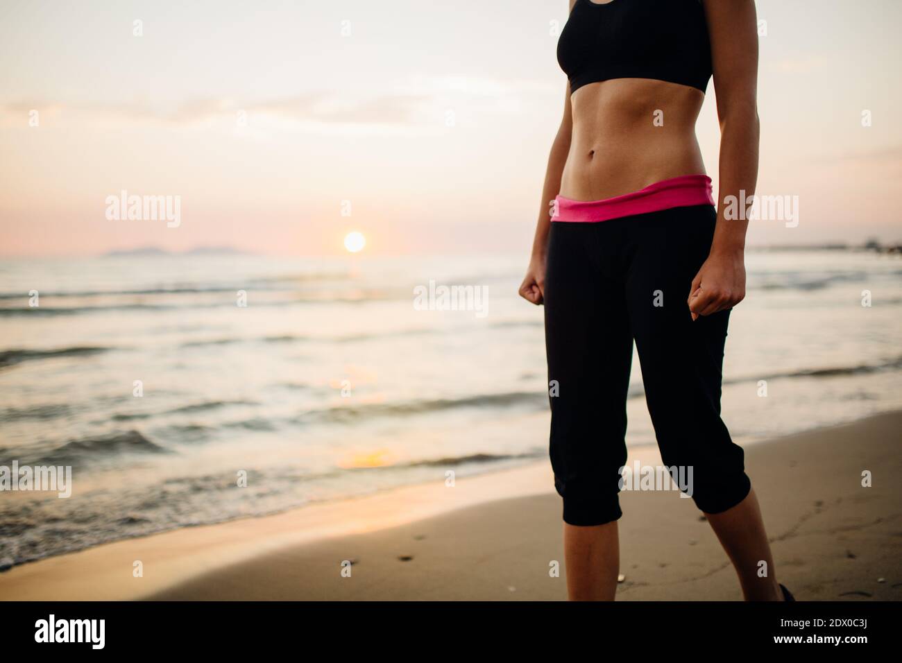 Runner woman jogging on beach in a sports bra top.Fit fitness woman training and working out outside as part of a healthy lifestyle.Fitness woman runn Stock Photo