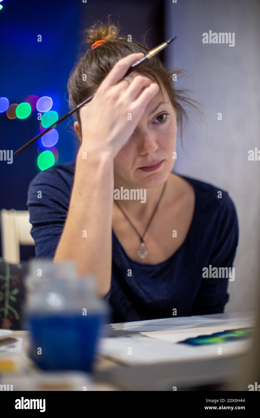 Portrait of a creative young woman seated at a table in an artists' workshop, looking pensively for inspiration Stock Photo