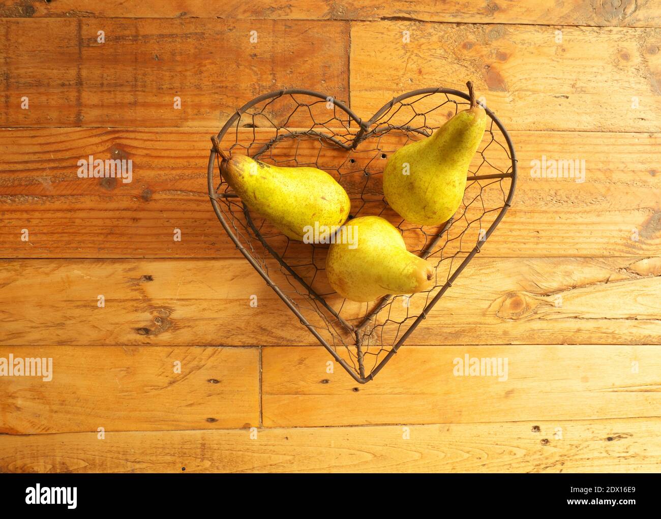 Photo of three pears inside a heart-shaped basket Stock Photo