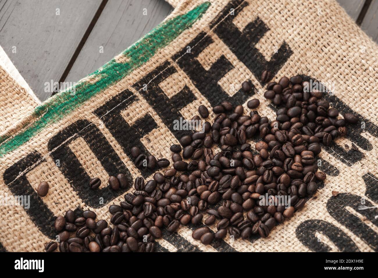 Dark roasted coffee beans lay on jute bag with standard black marking